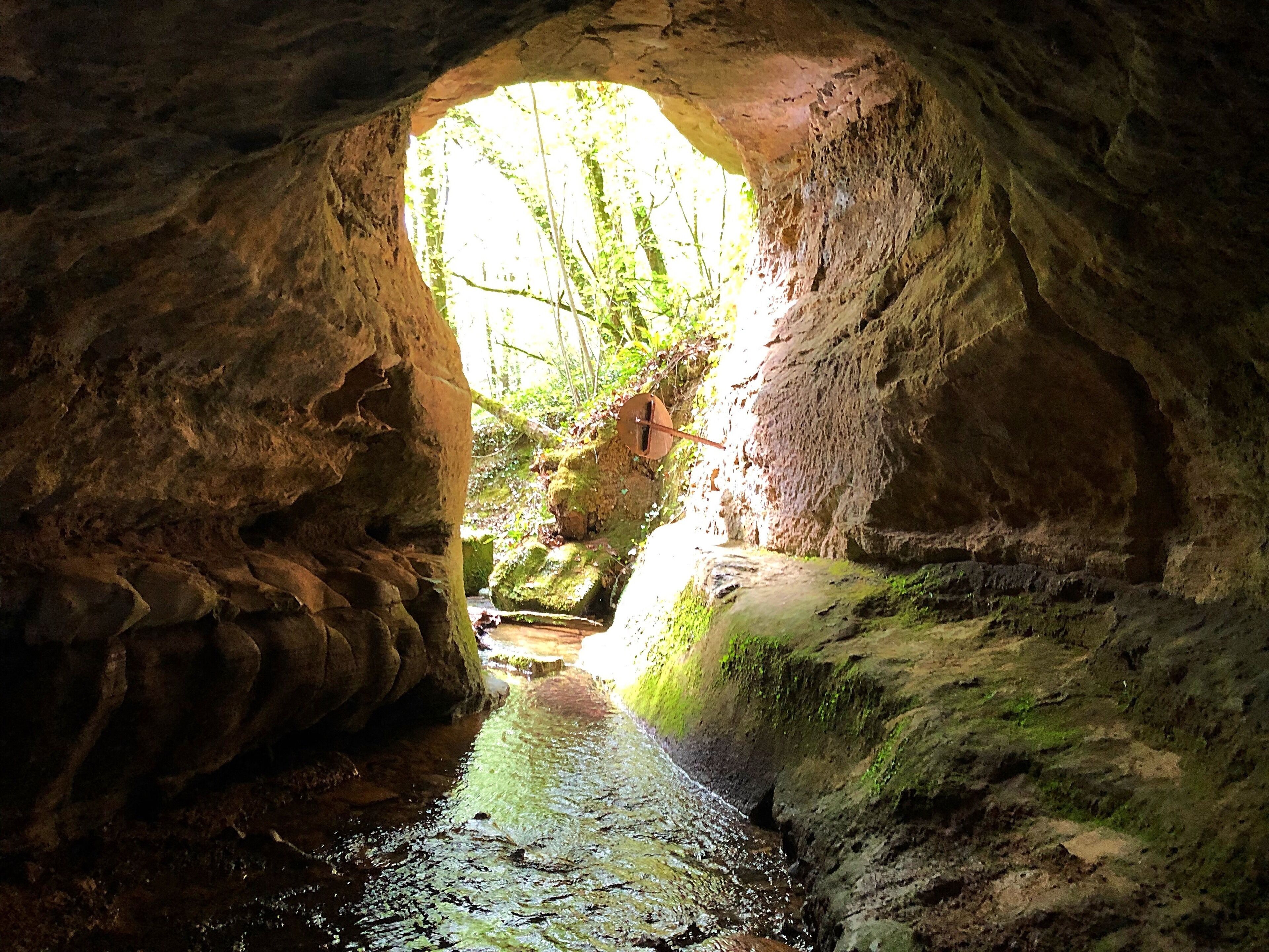 A cave entrance with a stream inside.