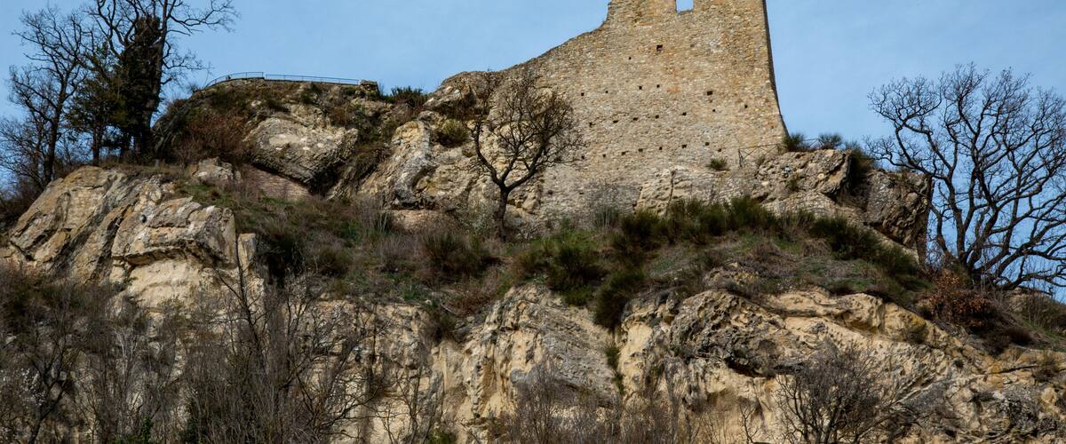 A historic stone castle ruin atop a rocky hill with sparse vegetation.