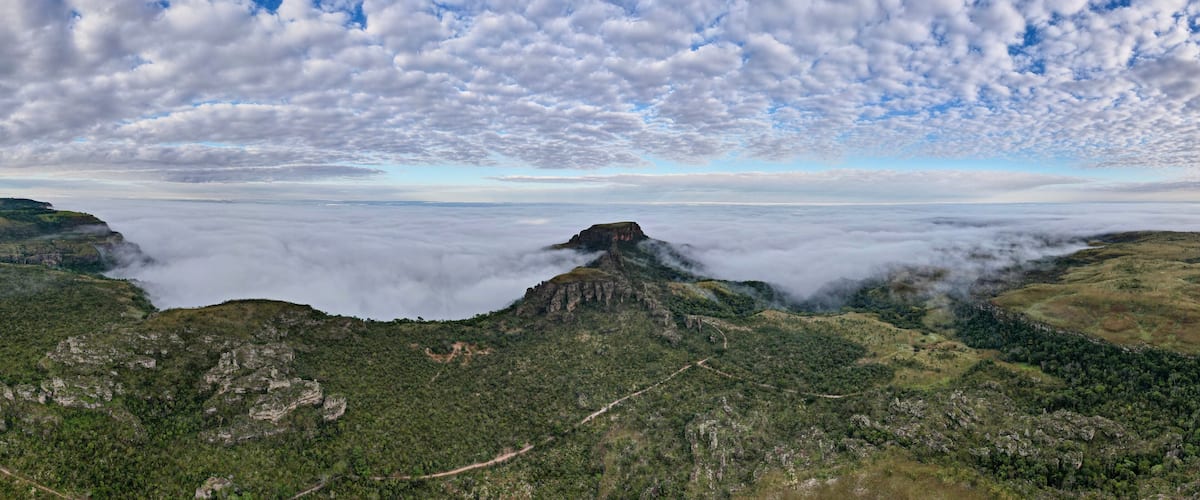 A mountainous landscape with a prominent peak, lush greenery, and a sea of clouds below.