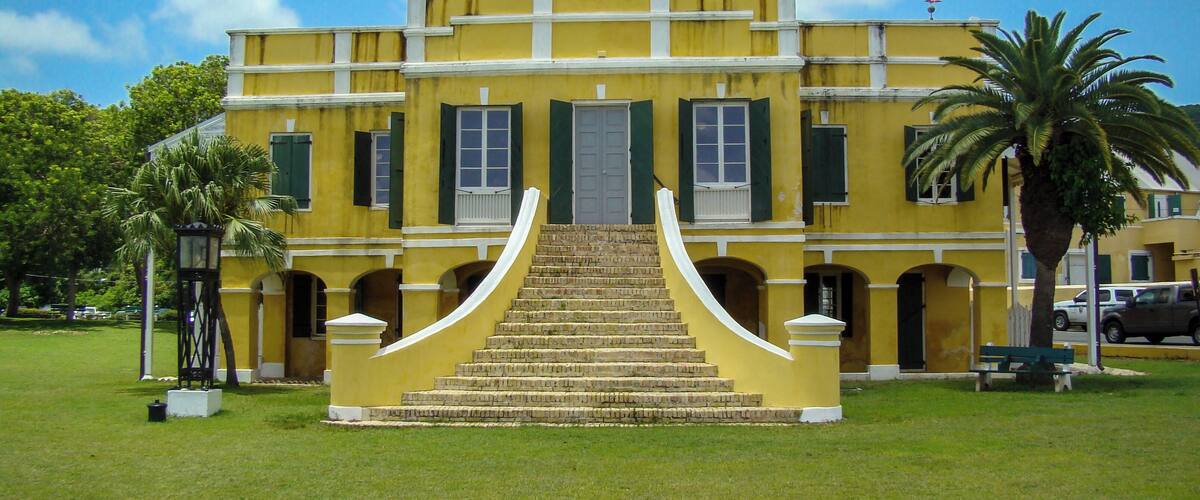 A yellow building with a central staircase and green shutters.