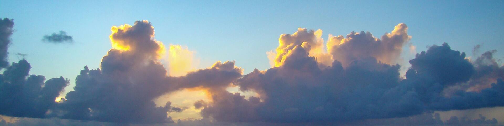 A calm sea with a clear sky and scattered clouds.