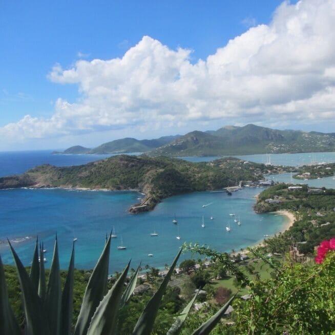 A coastal landscape with clear blue waters, boats, and lush greenery.