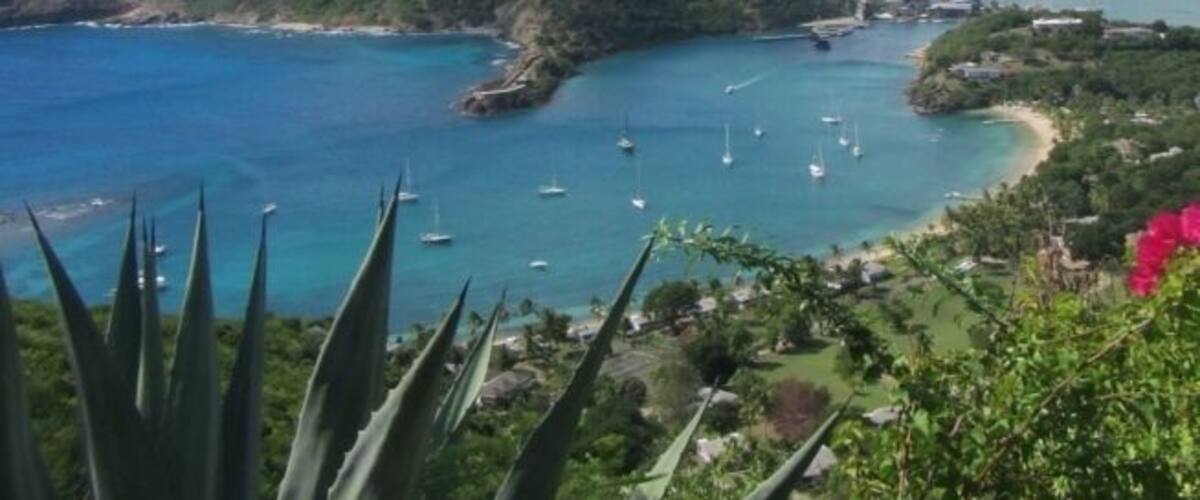 A coastal landscape with clear blue waters, boats, and lush greenery.