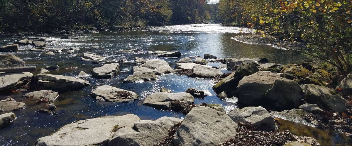 A river flowing through a rocky landscape with autumn foliage.