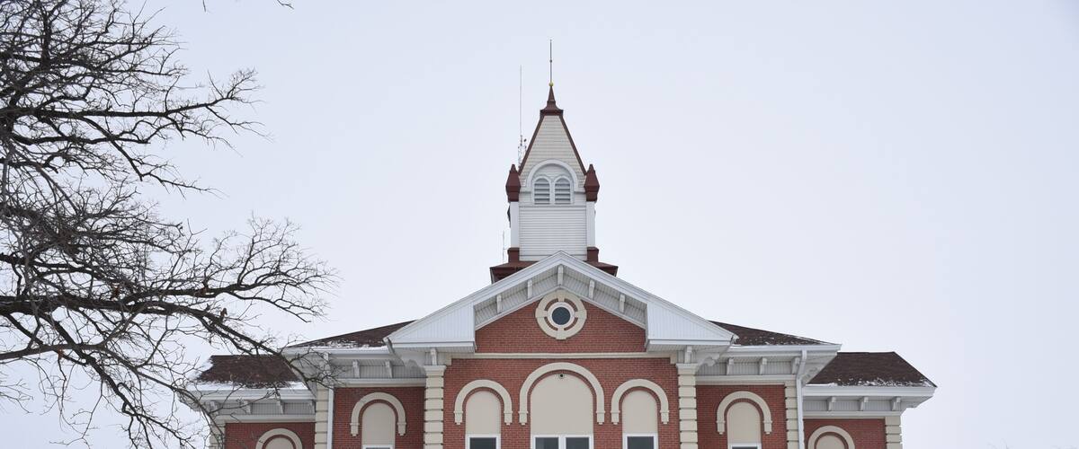 A brick courthouse with a steeple and a clock tower.