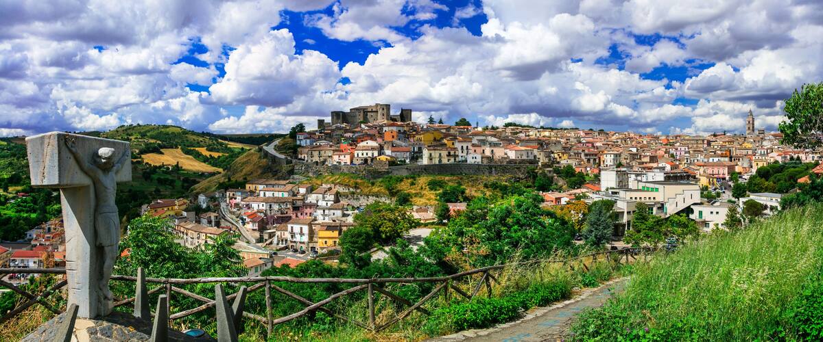 A historic town with a prominent church, a castle on a hill, and a winding road.