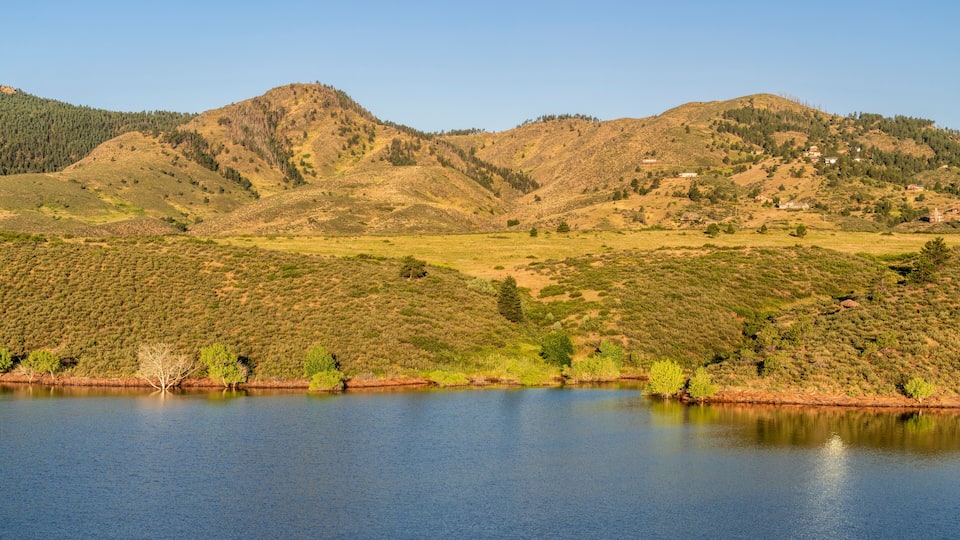 A lake surrounded by rolling hills with sparse vegetation and a few scattered houses.