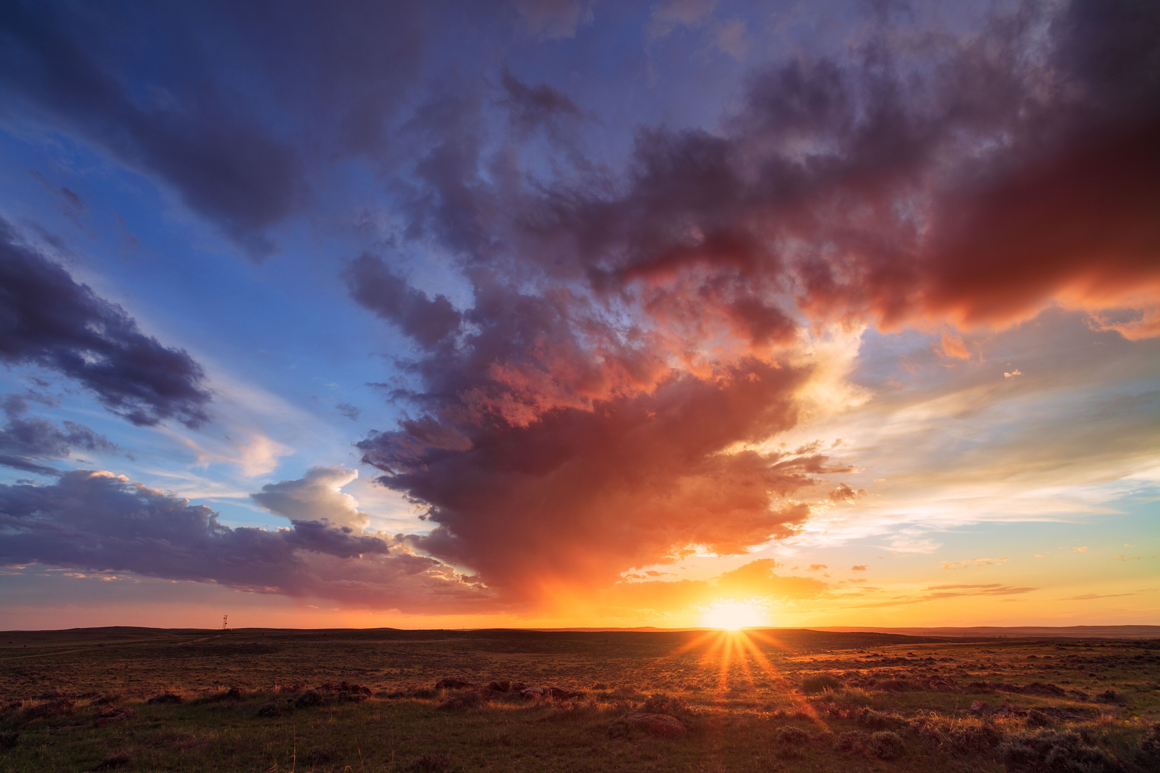 A sunset over a flat landscape with a prominent cloud formation.