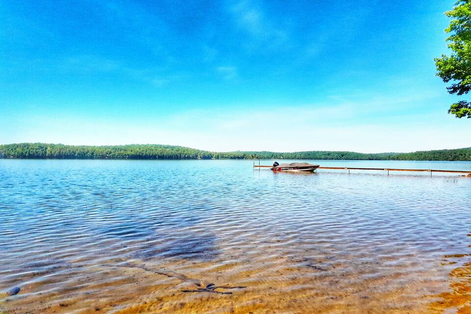 Un lago tranquilo con aguas transparentes, un muelle de madera y un bote.