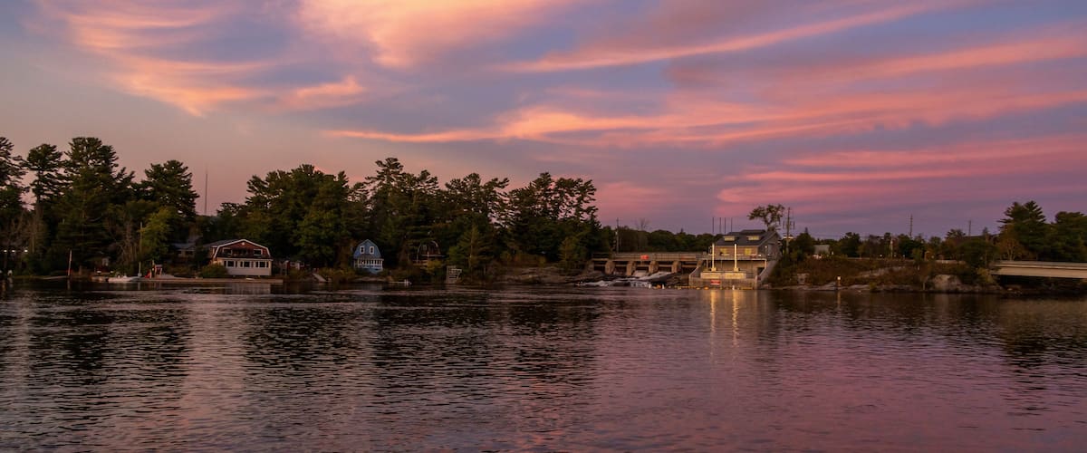Un lago tranquilo al atardecer, un puente y casas a lo largo de la orilla.