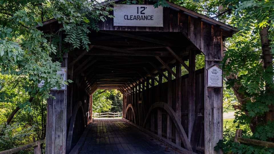 A wooden covered bridge with a 12' clearance sign.