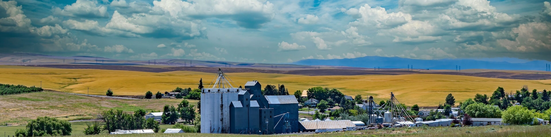 Paisagem rural com um silo de cereais, campos e uma pequena cidade.