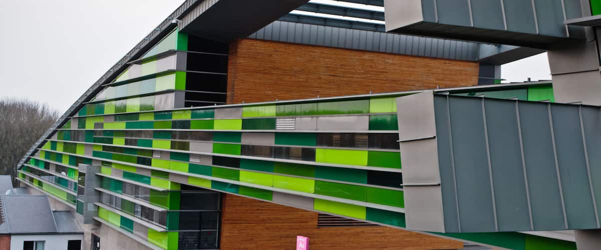 A modern building with green and white panels and a wooden facade.