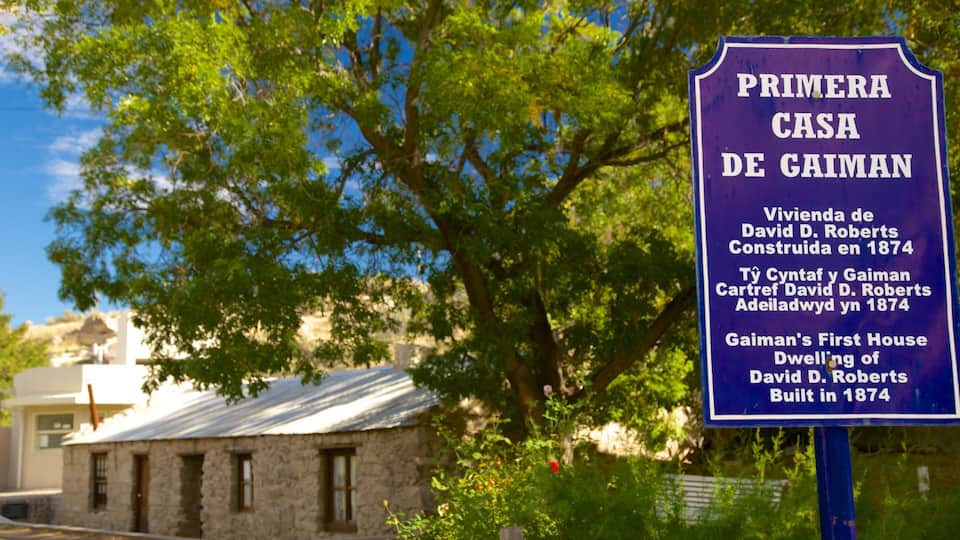 A historical marker for 'Primera Casa de Gaiman' with a stone building in the background.