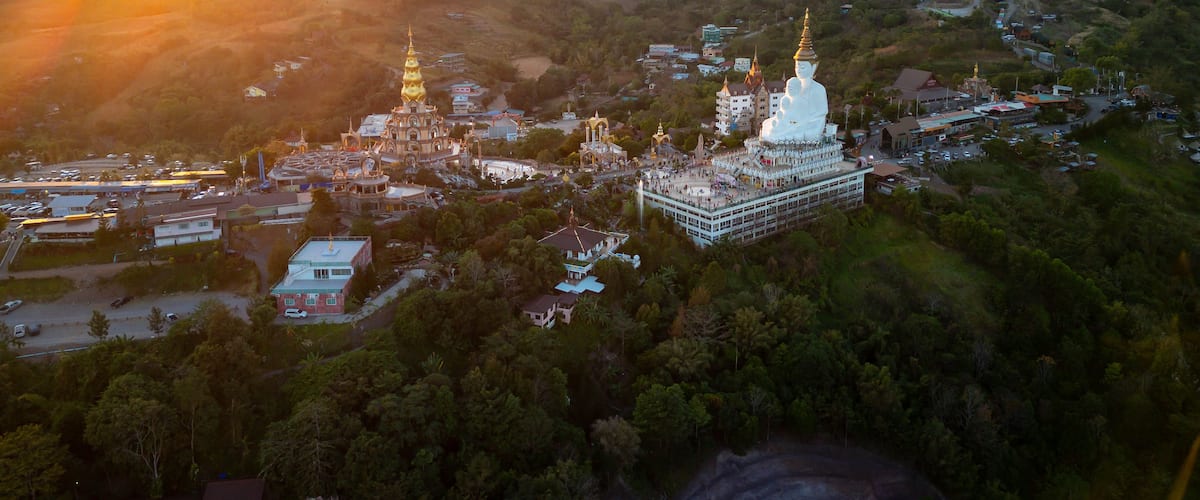 An aerial view of a temple complex surrounded by lush greenery and hills.