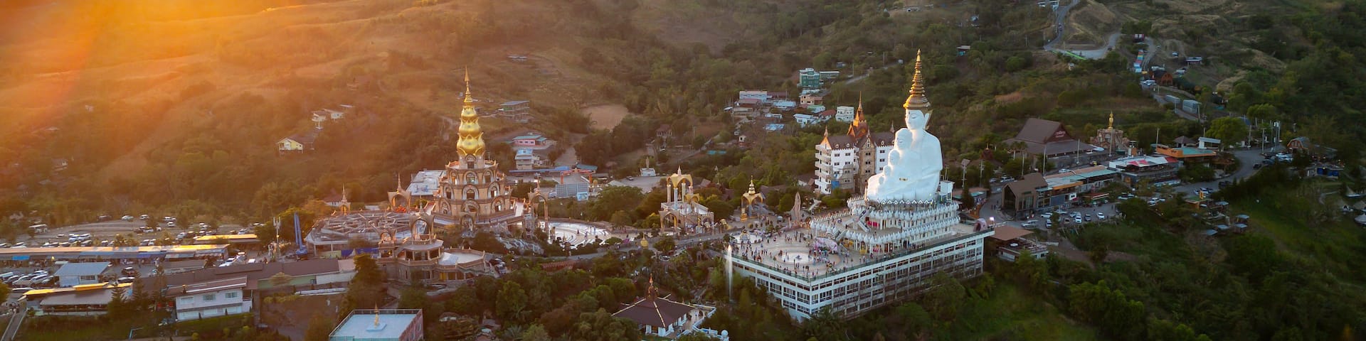 An aerial view of a temple complex surrounded by lush greenery and hills.