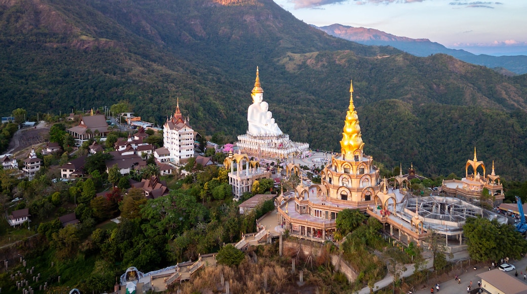 Un paysage montagneux avec un ensemble de temples caractérisé par des flèches dorées et des dômes blancs.