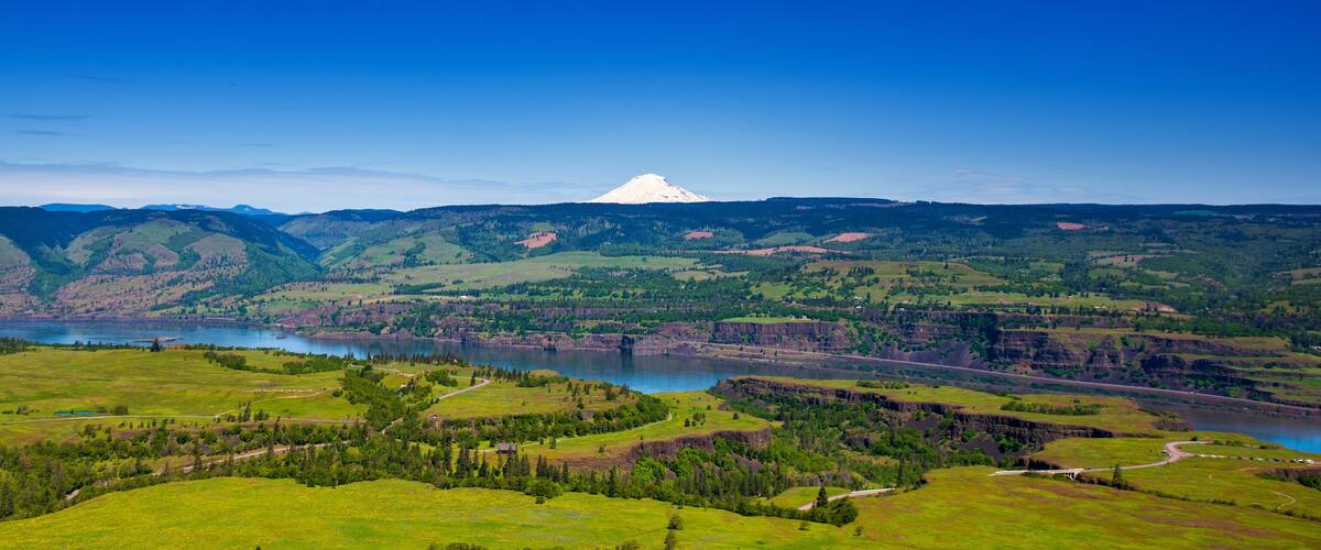 A mountainous landscape with a lake and a prominent snow-capped peak.
