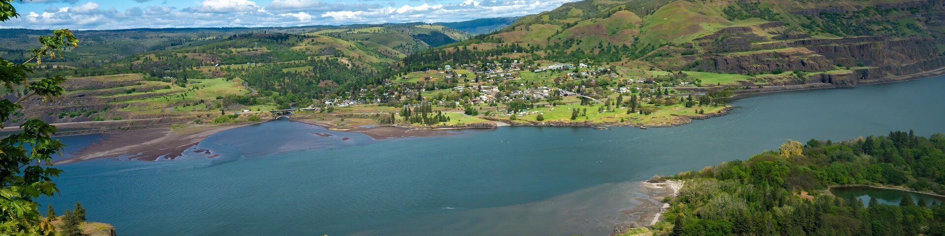 Un lago rodeado de colinas, un pueblo pequeño y una carretera.
