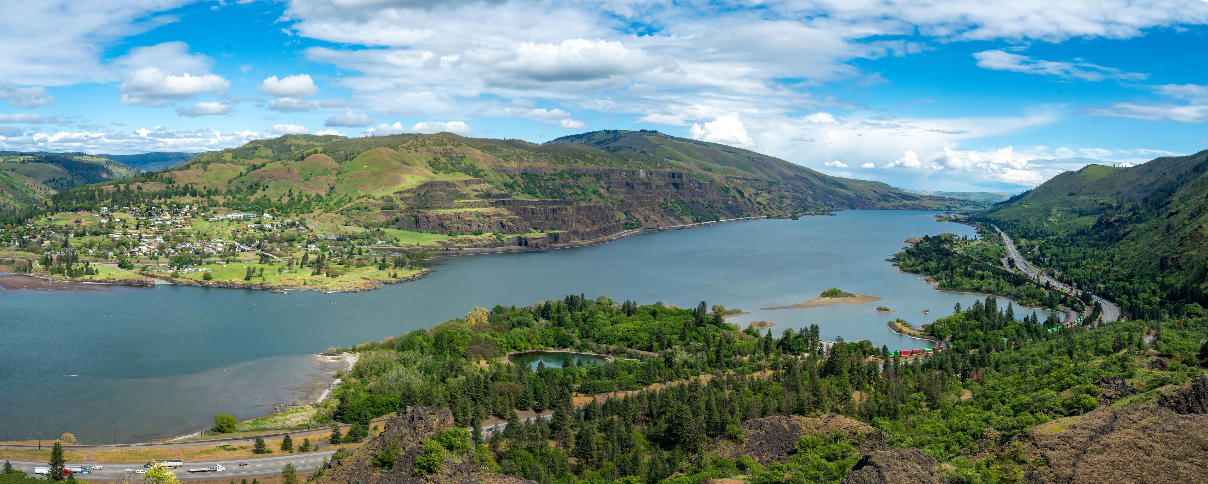 A lake surrounded by hills, a small town, and a winding road.