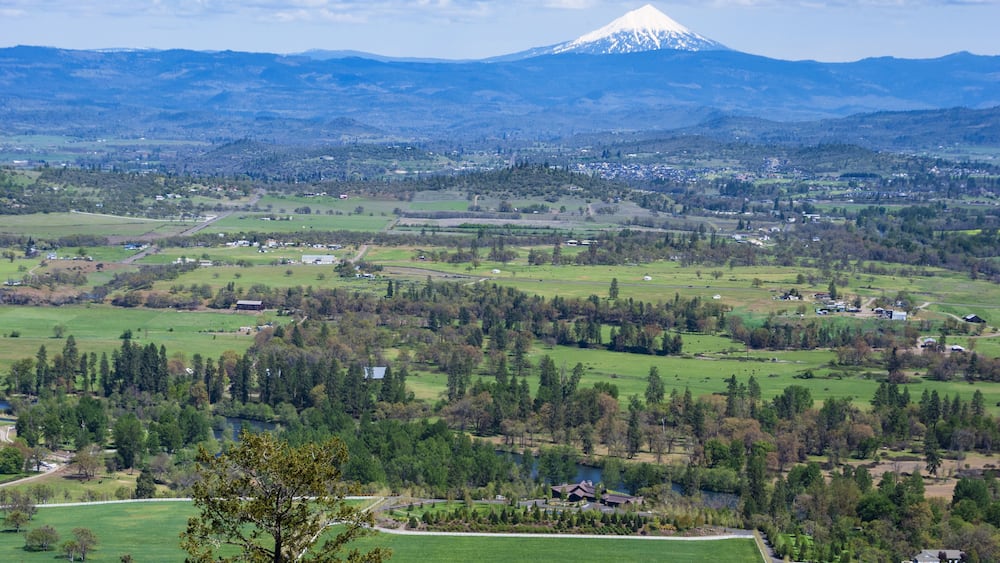 A snow-capped mountain, a valley with scattered houses, and a river.