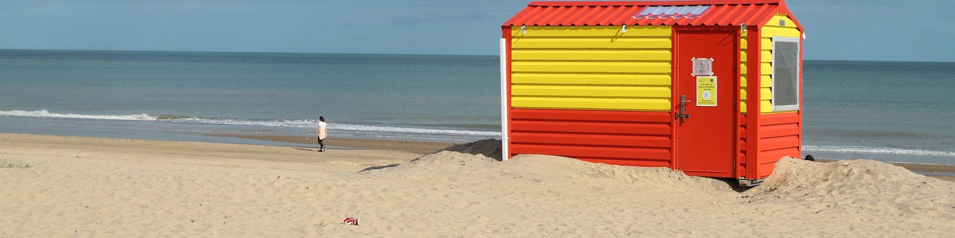 Orange and yellow lifeguard hut on Brittas Bay beach, County Wicklow, Ireland with overcast sky backdrop