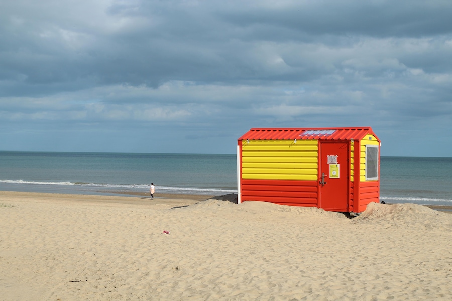 Orange and yellow lifeguard hut on Brittas Bay beach, County Wicklow, Ireland with overcast sky backdrop