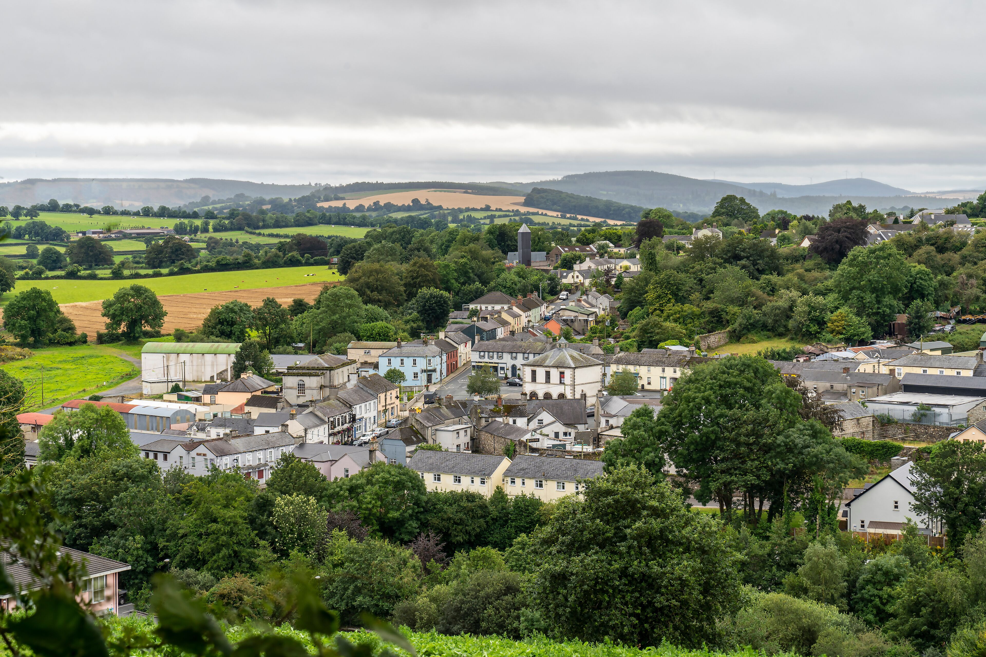 A rural village with houses, fields, and rolling hills in the background.