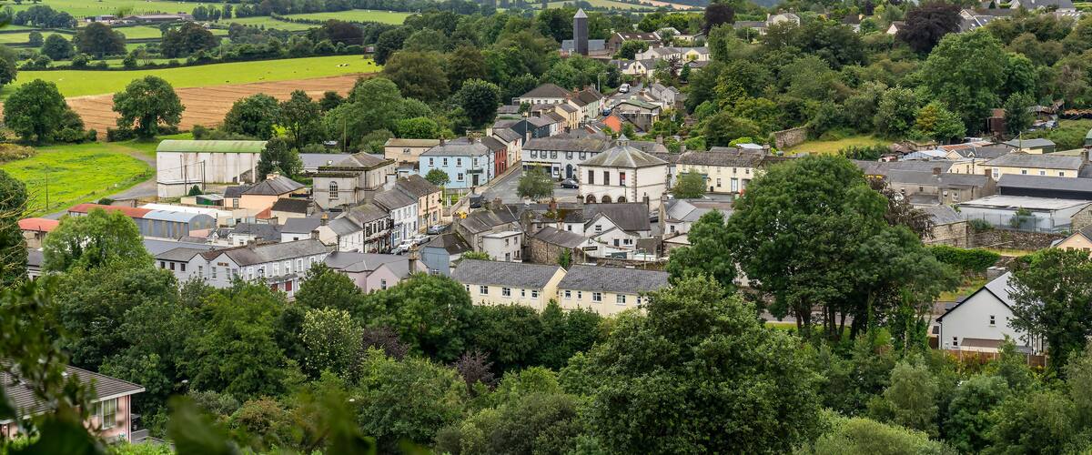A rural village with houses, fields, and rolling hills in the background.