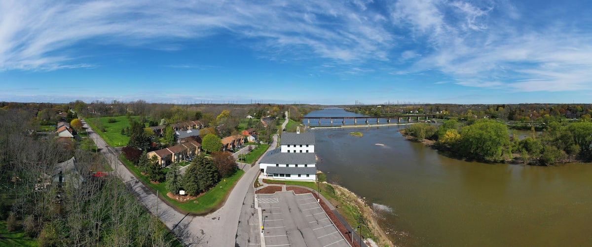 A river with a bridge, a parking lot, and a building with a green lawn.