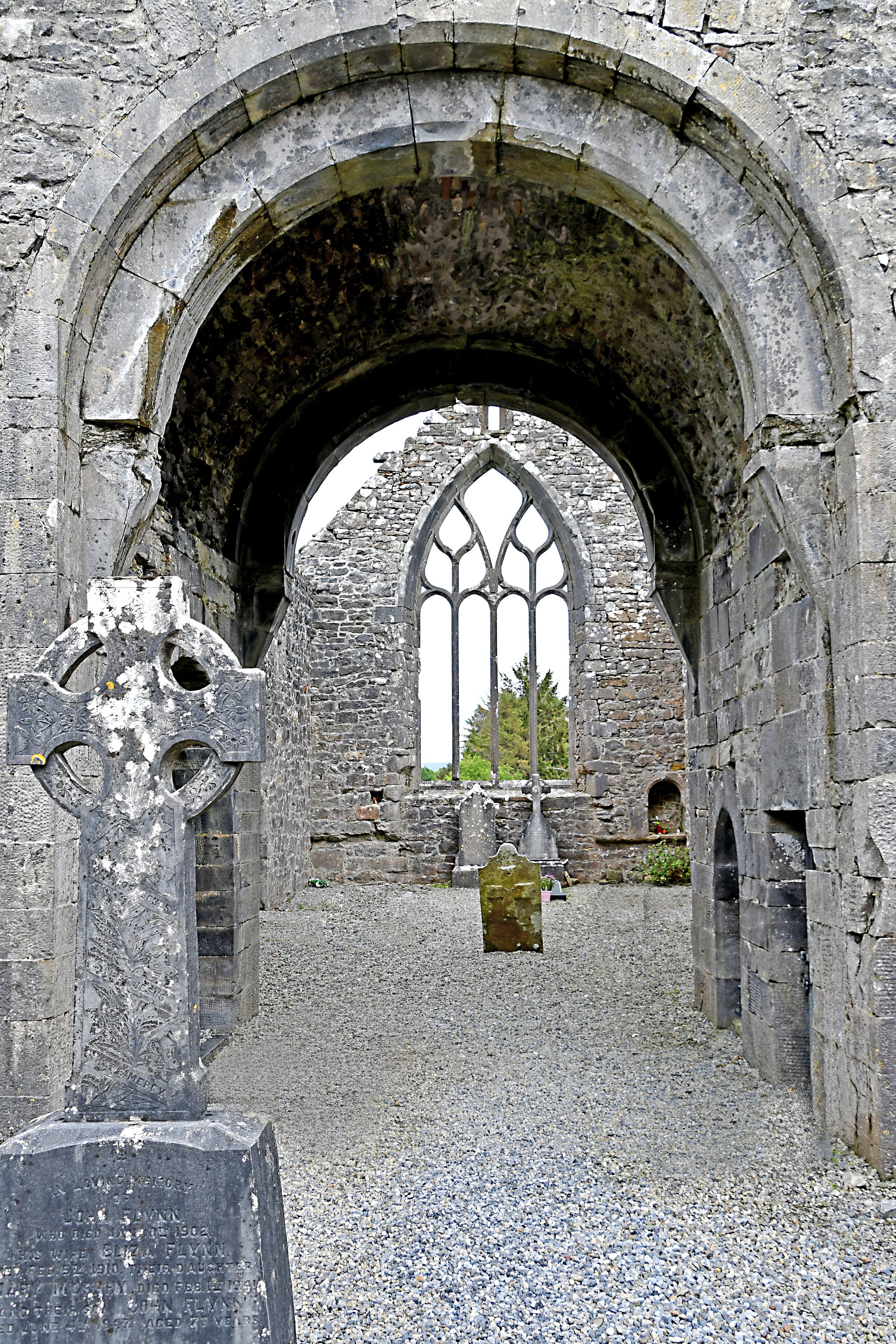 Una antigua estructura de piedra con un gran arco de entrada y una ventana gótica.