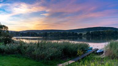 colorful sunset over lake landscape with small rowboats