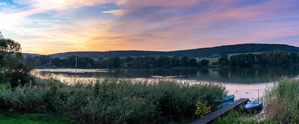 A lake at sunset with a wooden dock and boats.