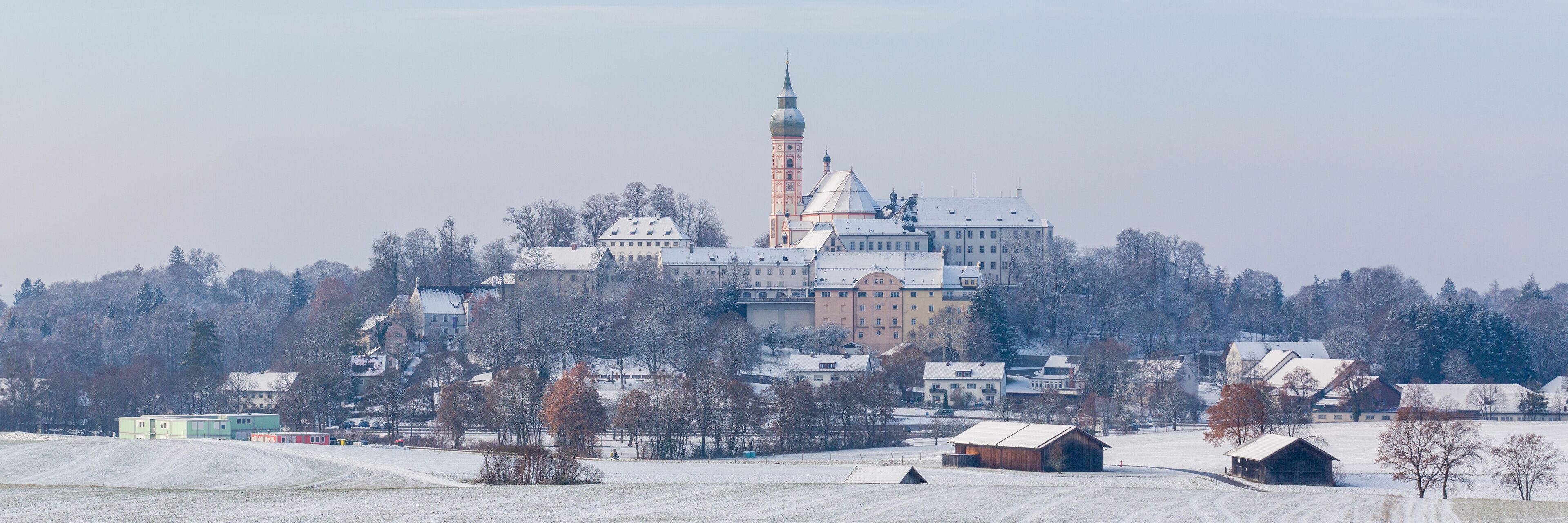 A snow-covered landscape with a prominent church featuring a tall bell tower and a domed roof.