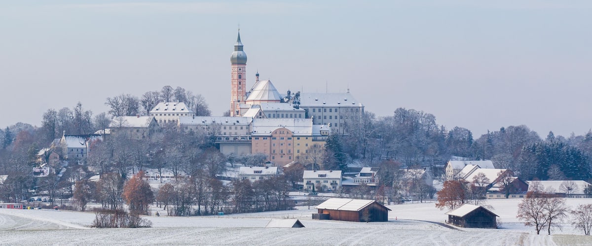 A snow-covered landscape with a prominent church featuring a tall bell tower and a domed roof.