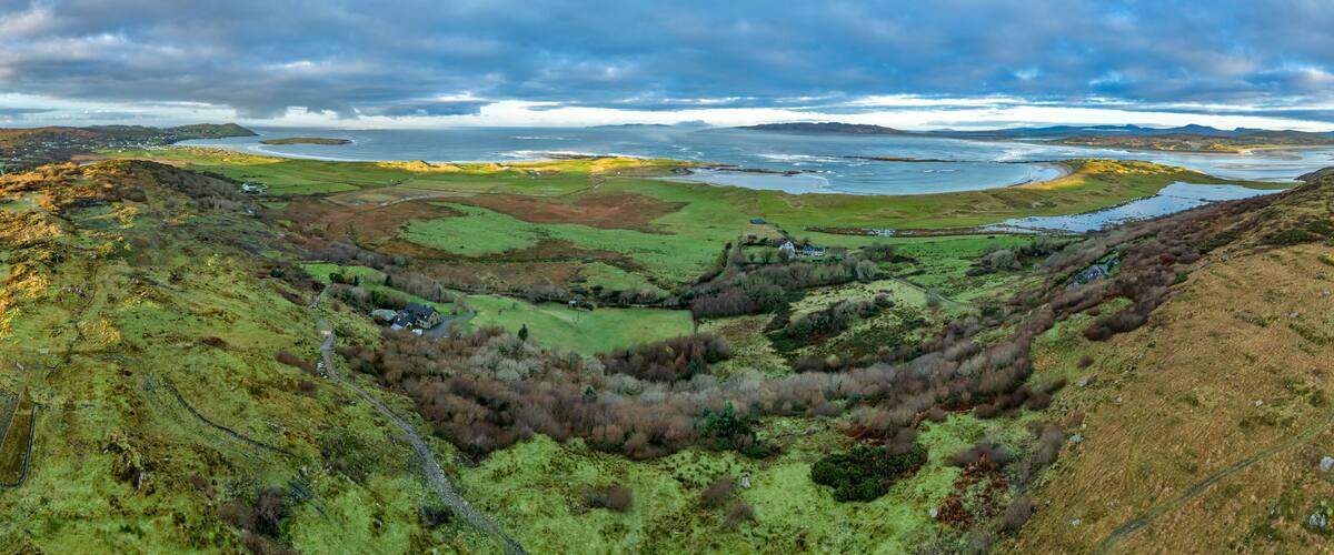 A coastal landscape with rolling hills, a river, and a distant shoreline.