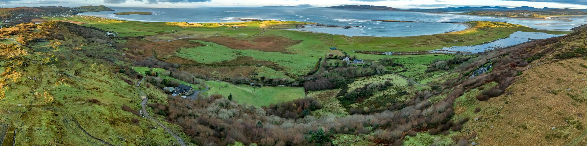 A coastal landscape with rolling hills, a river, and a distant shoreline.