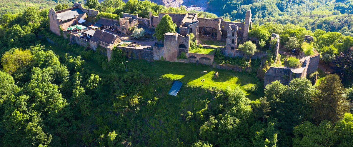 Vista aérea de un castillo histórico rodeado de vegetación exuberante y un valle.