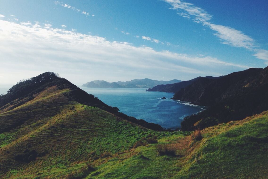 A coastal landscape with green hills and a clear blue sea.