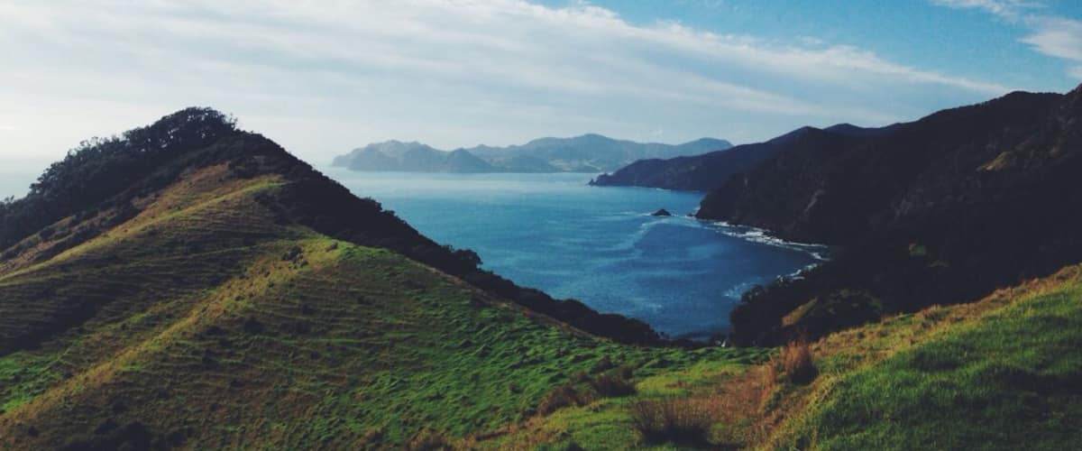 A coastal landscape with green hills and a clear blue sea.