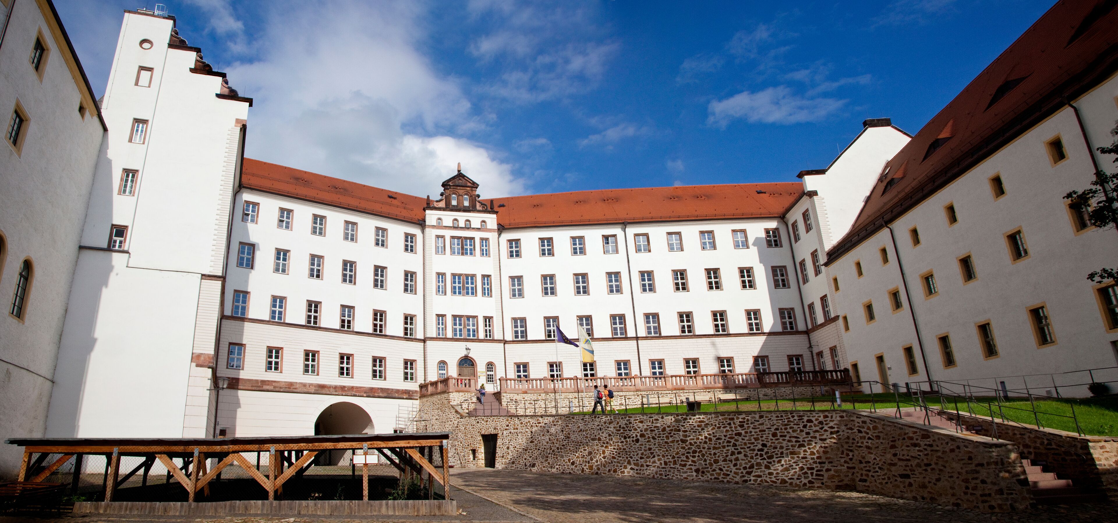 A historic building with a central courtyard, stone walls, and a flagpole.