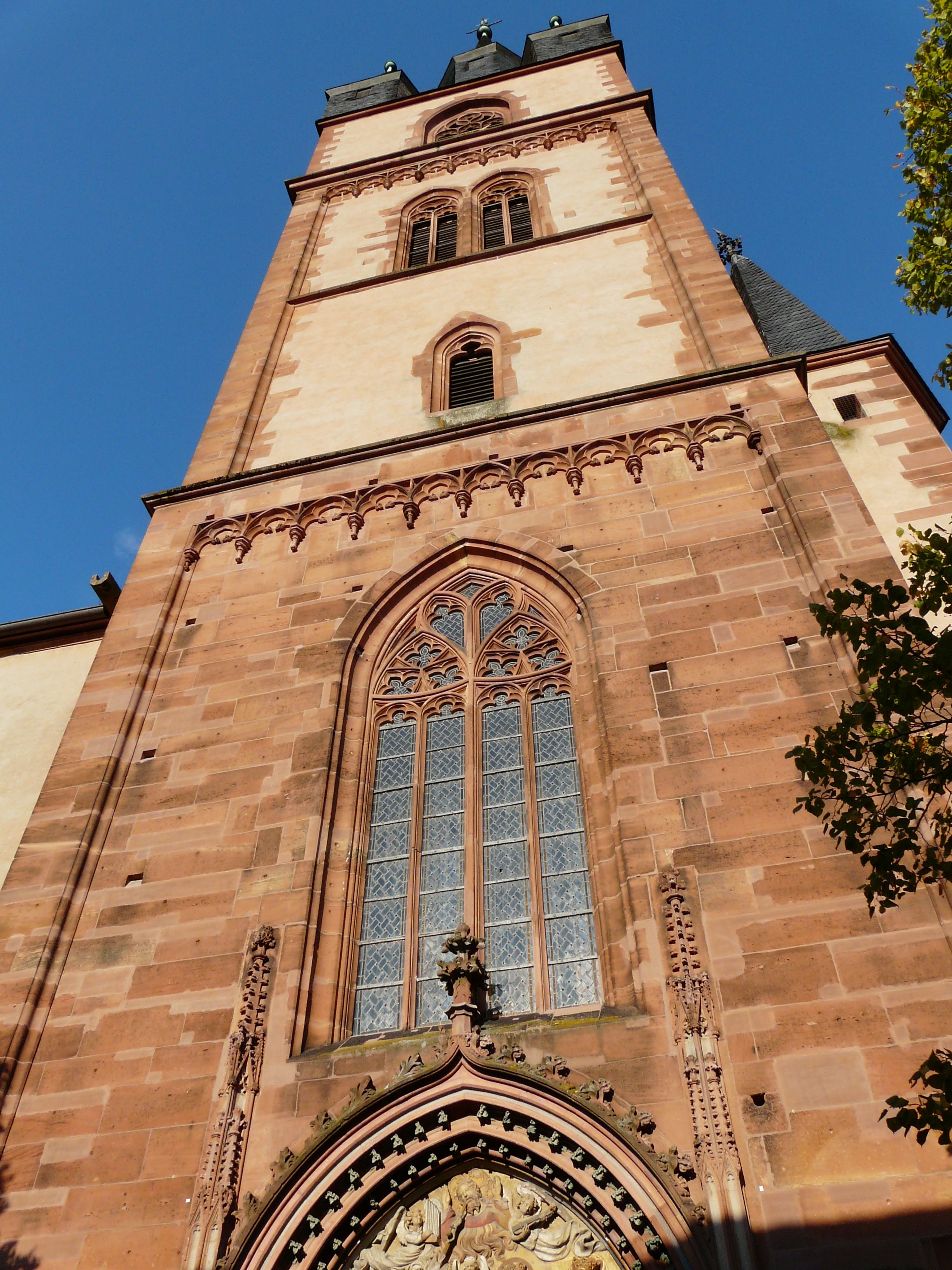 A tall, historic tower with intricate stonework and a large arched window.