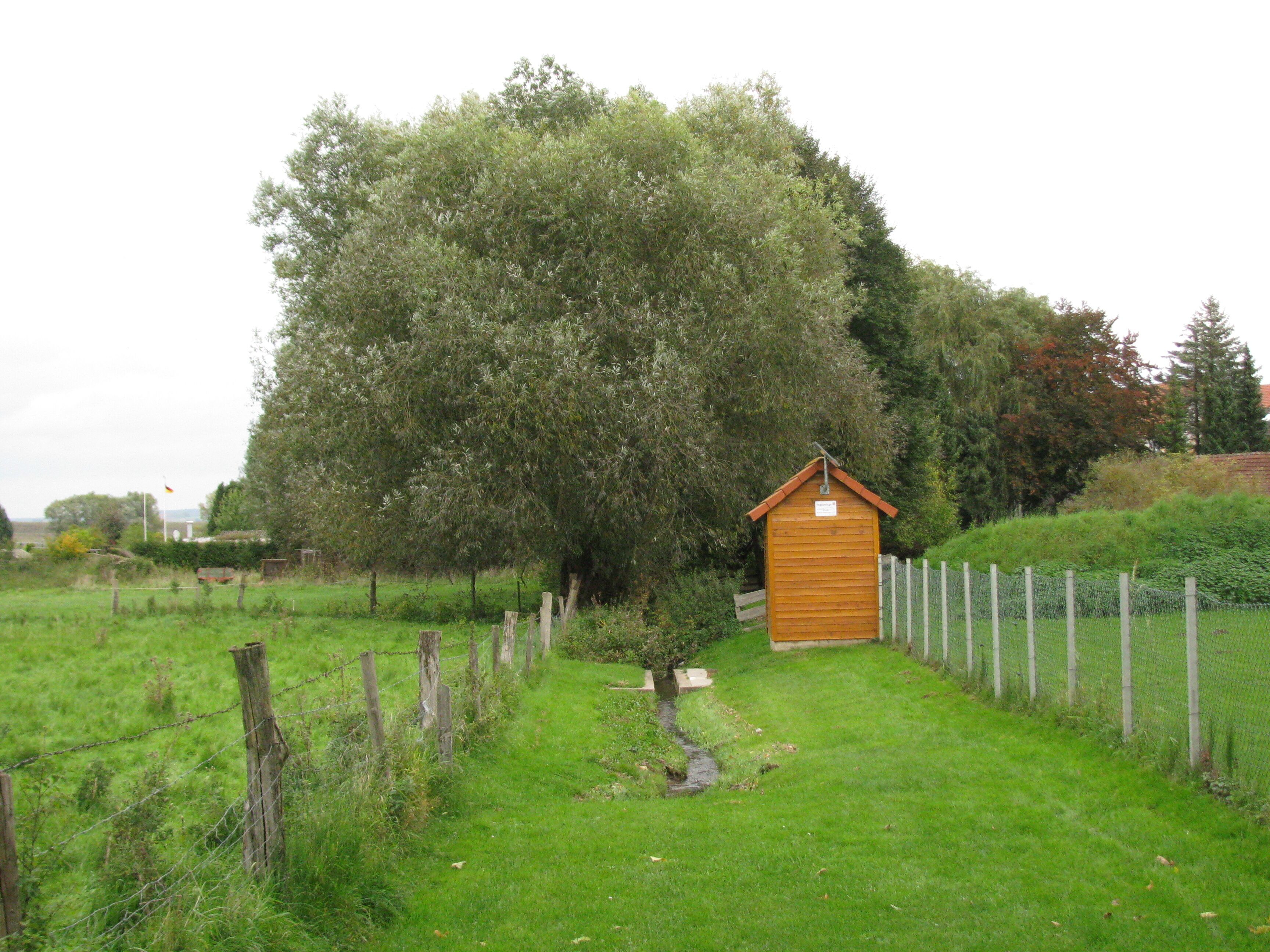 der Bach Glockenbrunnen unterhalb der Schäfergasse in Calden mit einem Pegelhaus
