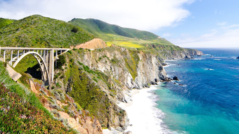 A coastal landscape with a bridge, cliffs, and ocean.