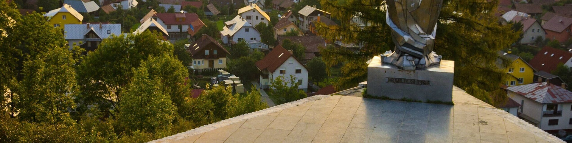 A statue on a hill overlooking a village.