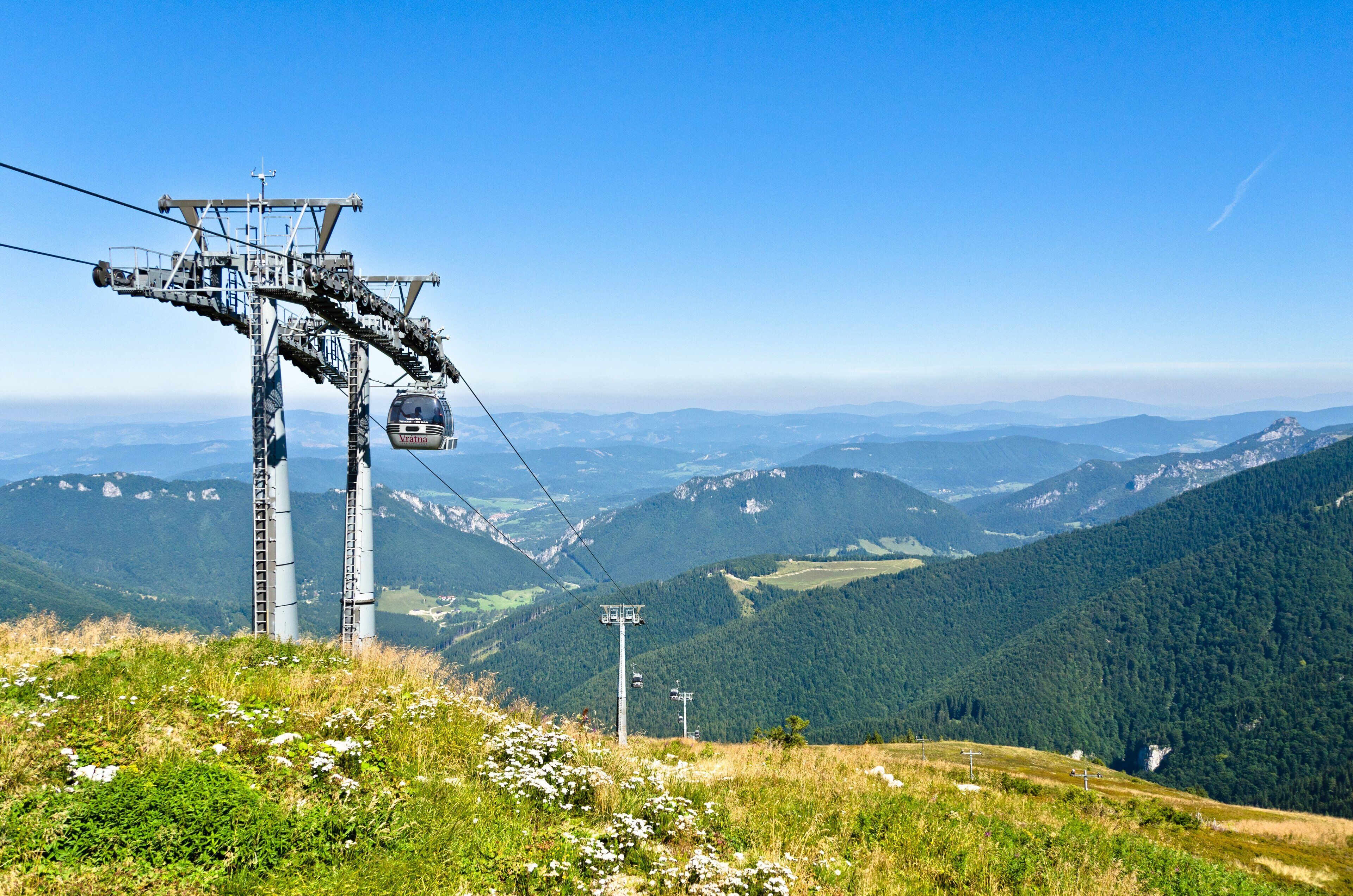 A cable car system in a mountainous area with lush greenery and distant peaks.