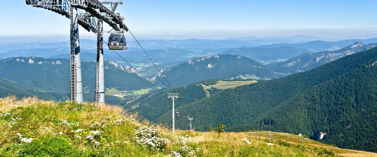 A cable car system in a mountainous area with lush greenery and distant peaks.