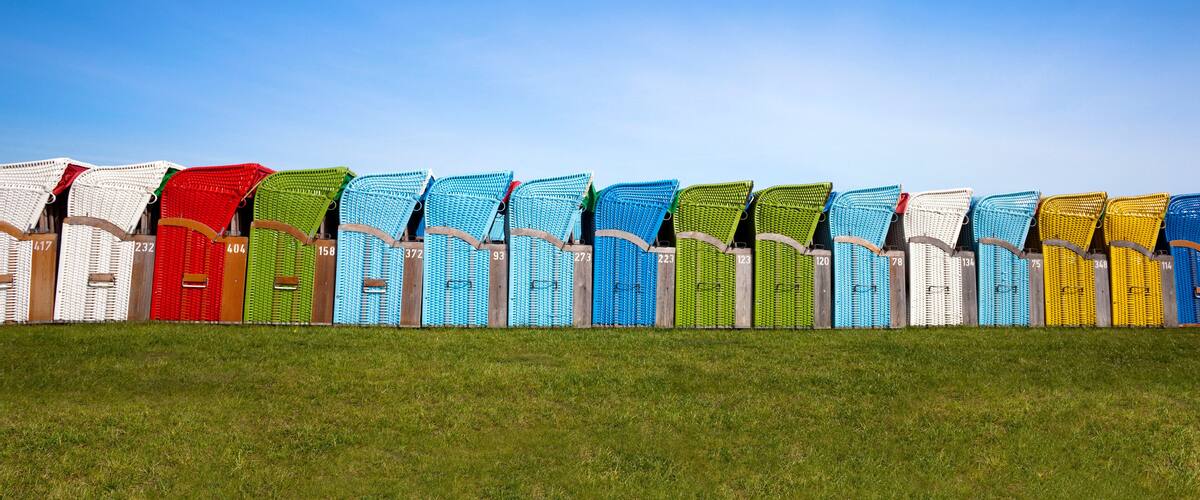 A row of colorful chairs with numbers on them, arranged on a grassy hill.