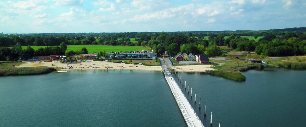 A long bridge over a river with buildings and greenery in the background.