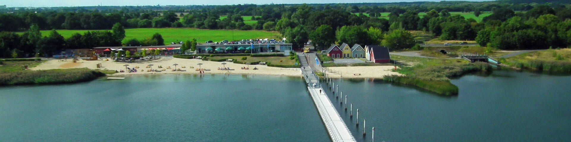 Un largo puente sobre un río, con edificios y vegetación al fondo.